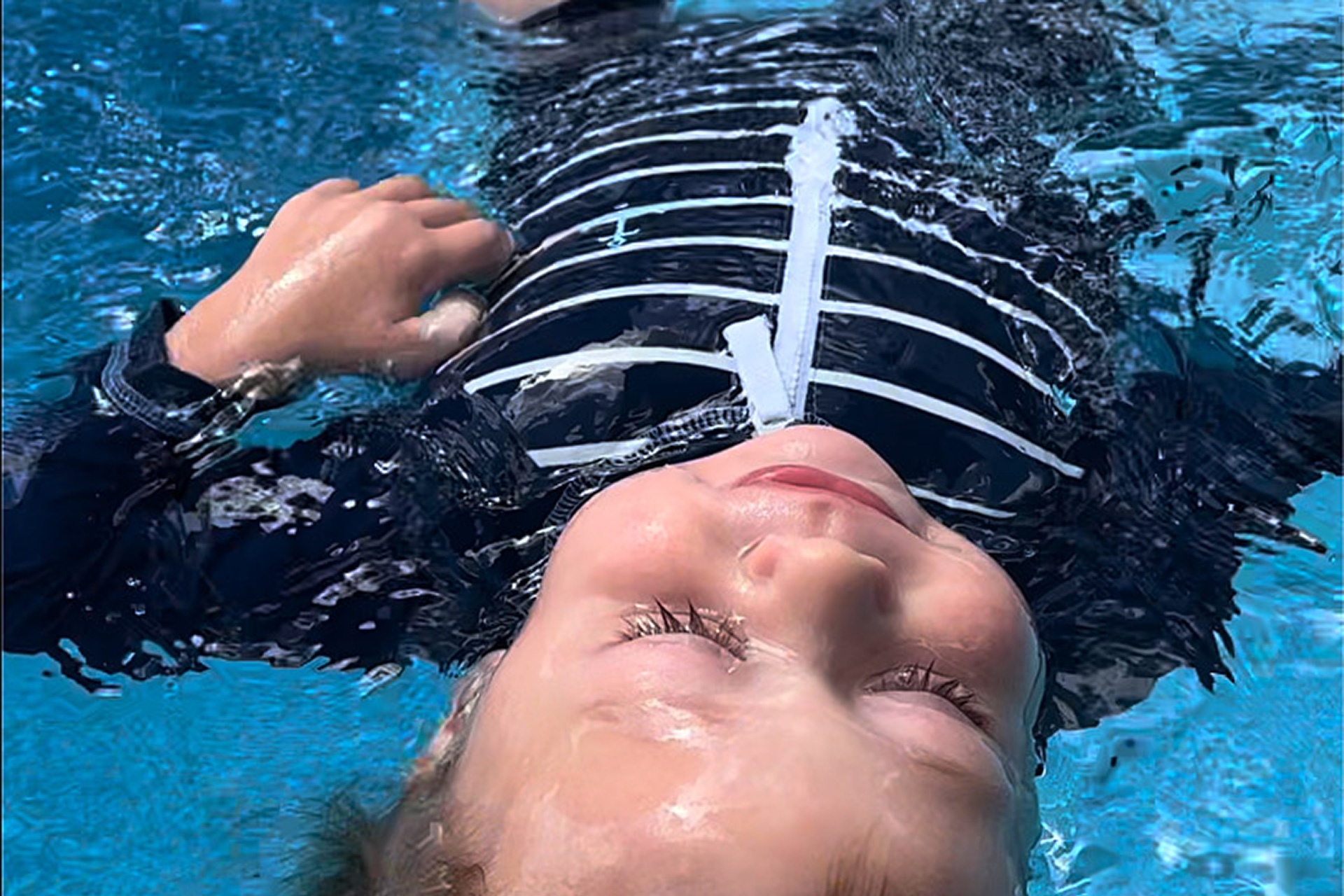 A young child floats confidently in a backyard pool