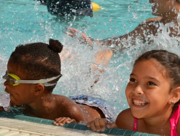 Young children taking swimming lessons and smiling